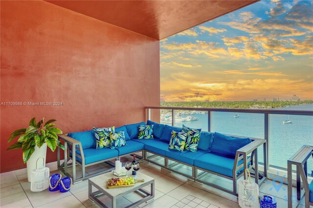 balcony at dusk featuring an outdoor living space and a water view