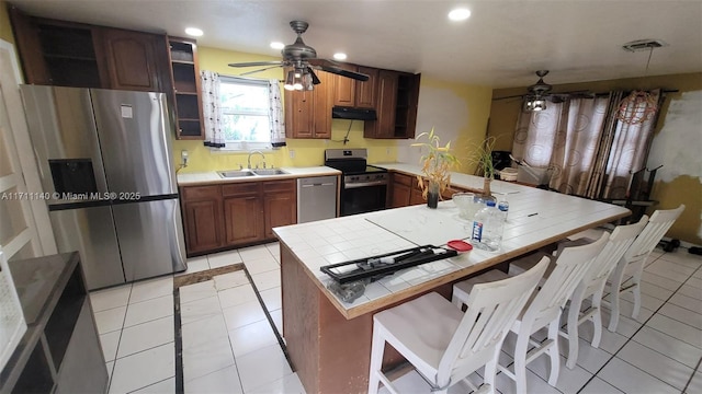 kitchen with a kitchen breakfast bar, sink, light tile patterned floors, appliances with stainless steel finishes, and kitchen peninsula