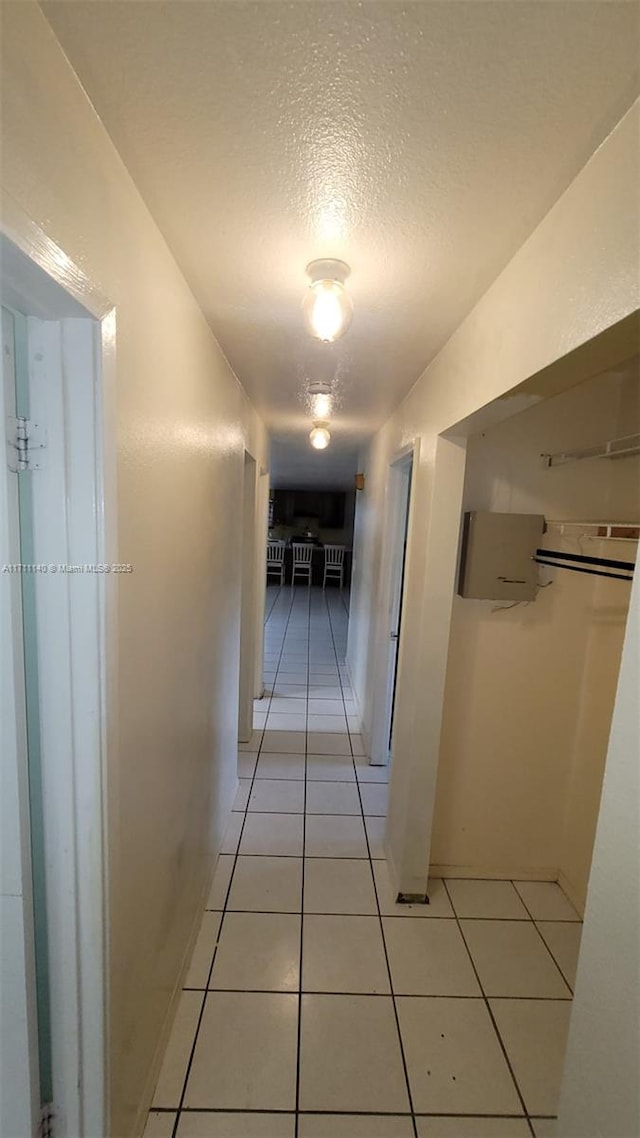 corridor featuring light tile patterned floors and a textured ceiling