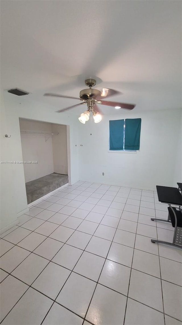 empty room with ceiling fan and light tile patterned floors