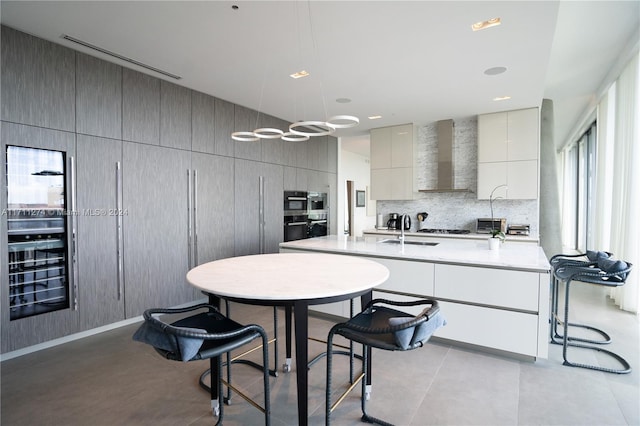 kitchen with decorative light fixtures, plenty of natural light, wall chimney exhaust hood, and sink