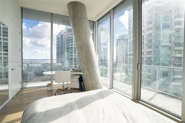 bedroom featuring access to outside, expansive windows, and hardwood / wood-style flooring