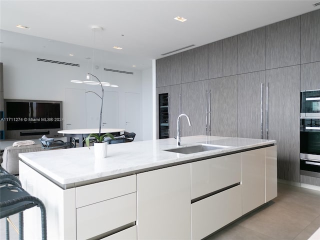 kitchen featuring light stone counters, stainless steel appliances, sink, a center island with sink, and wine cooler