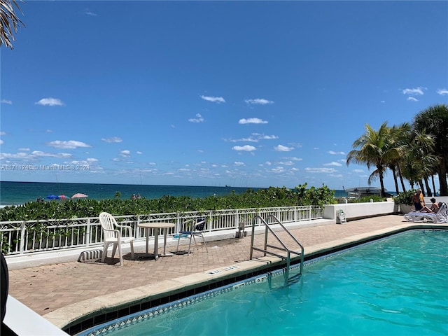 view of pool with a patio area and a water view