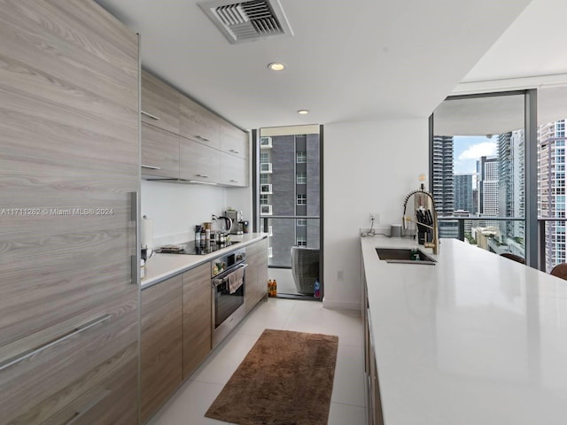 kitchen with black electric stovetop, sink, expansive windows, and stainless steel oven