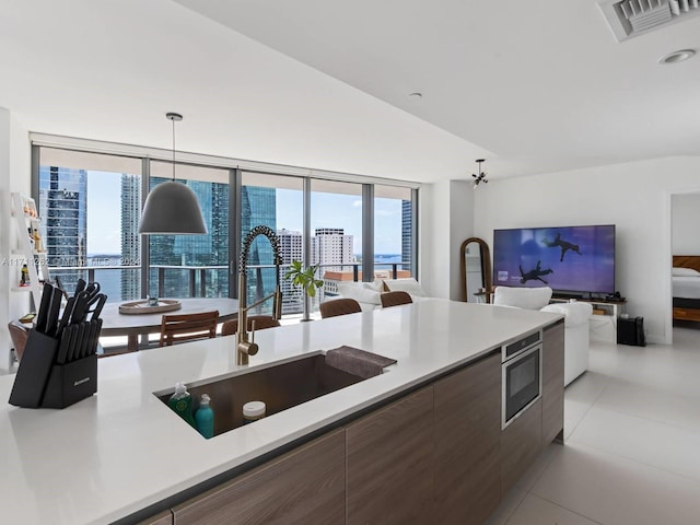 kitchen featuring pendant lighting, stainless steel microwave, sink, vaulted ceiling, and ceiling fan