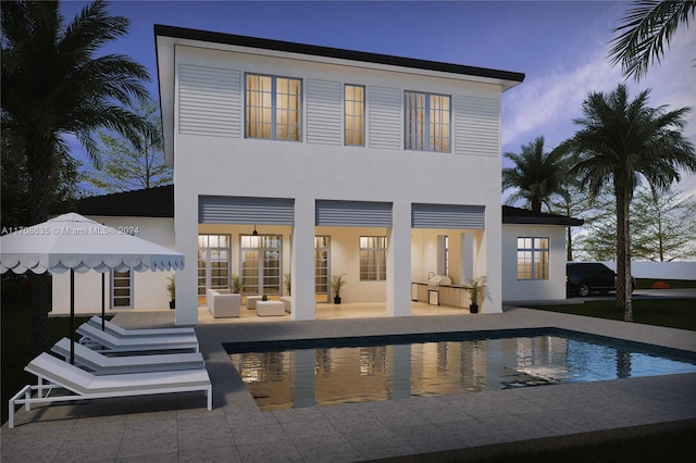 back house at dusk with french doors, a patio, and an outdoor hangout area