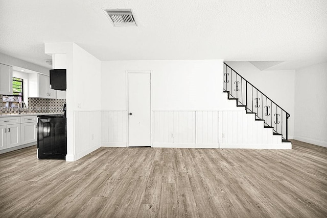 interior space with a textured ceiling, light hardwood / wood-style flooring, and sink