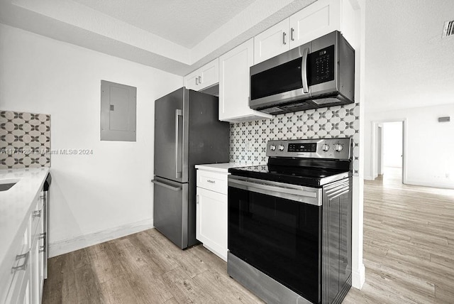 kitchen with decorative backsplash, stainless steel appliances, light hardwood / wood-style flooring, electric panel, and white cabinetry