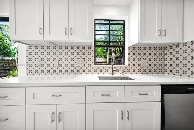 kitchen with tasteful backsplash, white cabinetry, sink, and stainless steel dishwasher