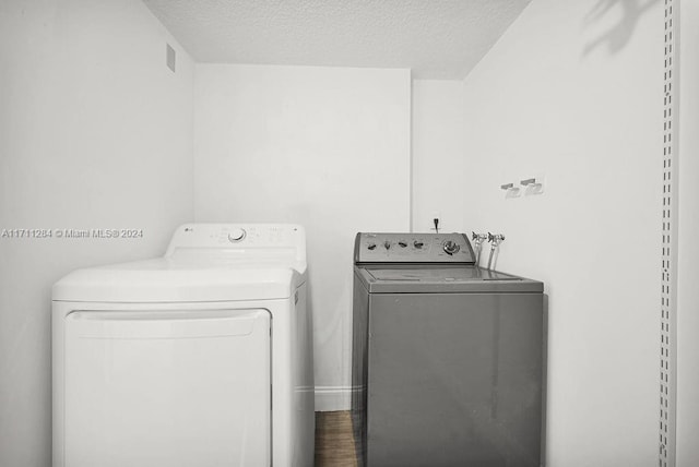 clothes washing area with a textured ceiling and independent washer and dryer