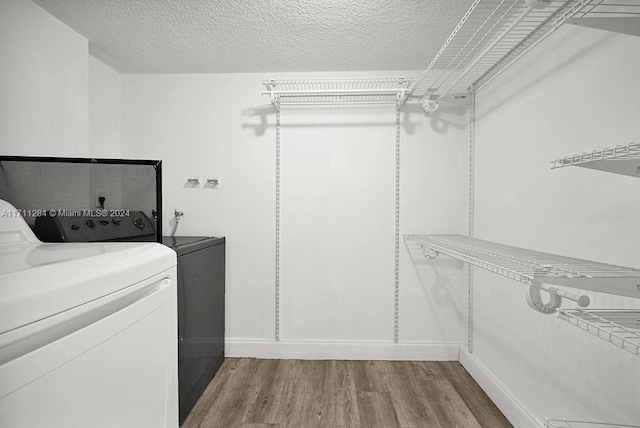 washroom with wood-type flooring, a textured ceiling, and independent washer and dryer