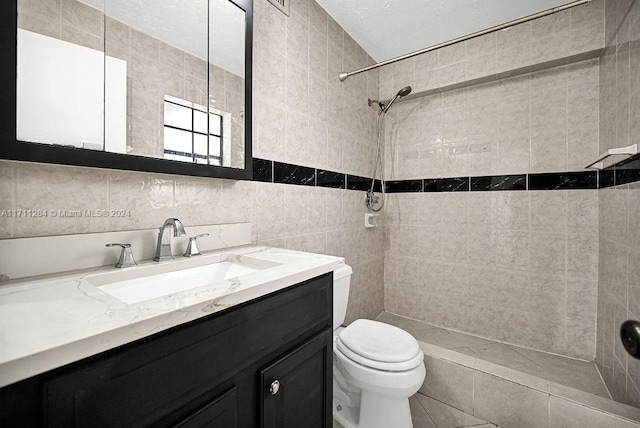 bathroom featuring a tile shower, vanity, toilet, and tile walls