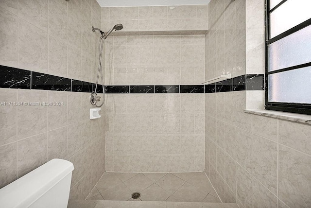 bathroom featuring tiled shower and toilet