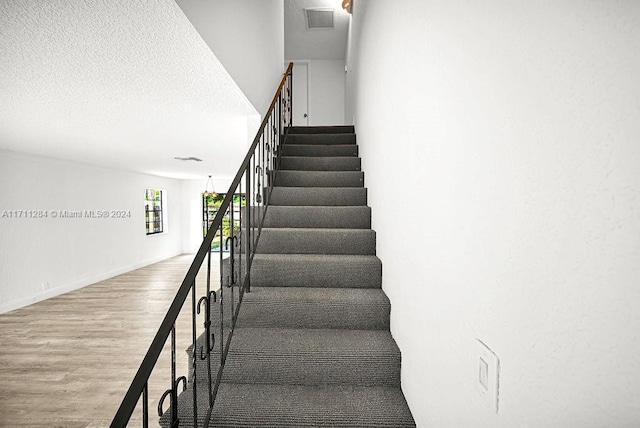 stairs featuring hardwood / wood-style floors and a textured ceiling