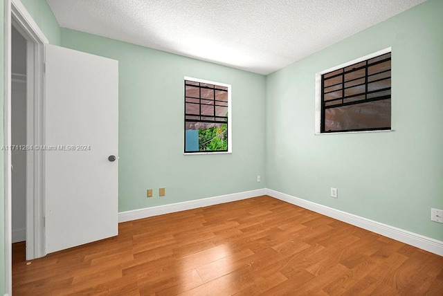 empty room with a textured ceiling and light hardwood / wood-style floors