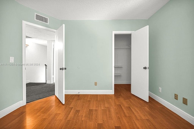 unfurnished bedroom featuring wood-type flooring, a textured ceiling, and a closet