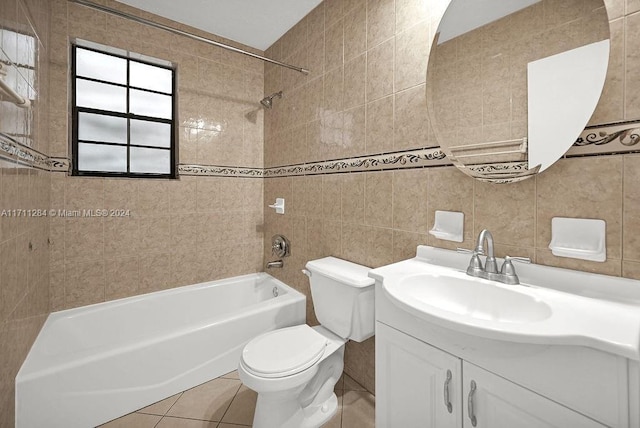 full bathroom featuring tile patterned flooring, toilet, vanity, tile walls, and tiled shower / bath