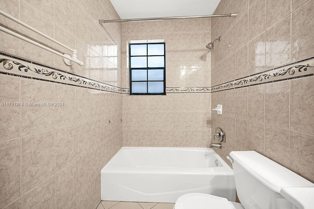 bathroom with tiled shower / bath, tile walls, and toilet