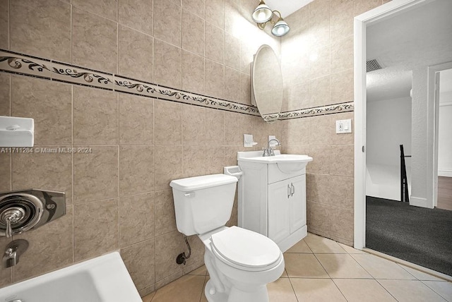 bathroom featuring toilet, vanity, tile patterned floors, and tile walls