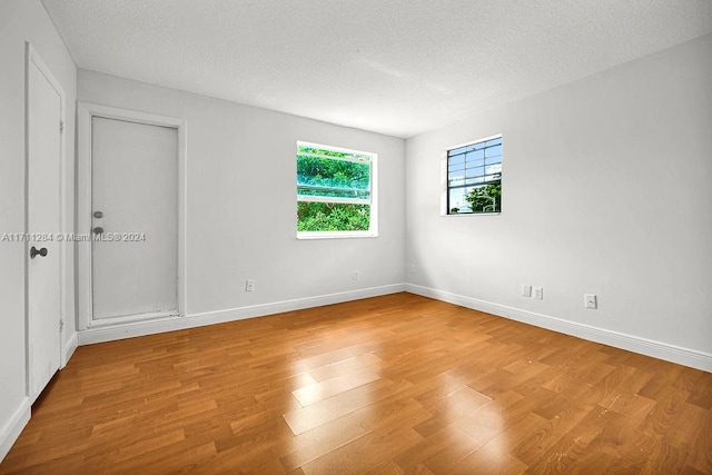 spare room with a textured ceiling and light wood-type flooring