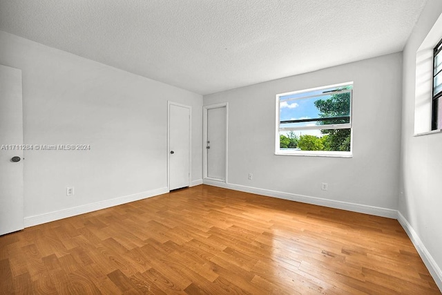 empty room with a textured ceiling and light hardwood / wood-style flooring