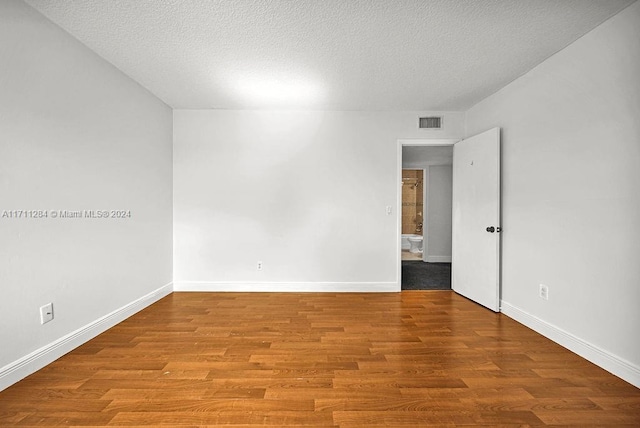 unfurnished room with light wood-type flooring and a textured ceiling