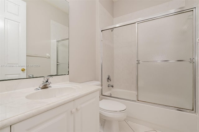 full bathroom with shower / bath combination with glass door, vanity, tile patterned flooring, and toilet