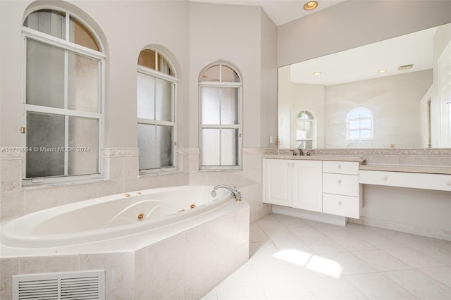 bathroom featuring tile patterned flooring, vanity, and tiled bath