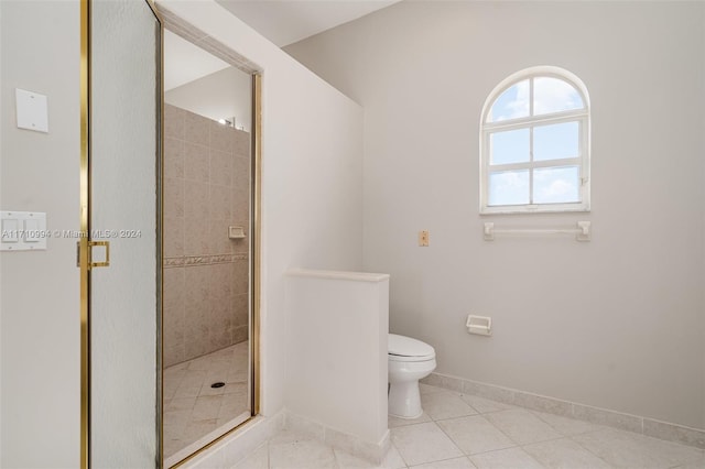 bathroom featuring toilet, tile patterned floors, and a shower with door