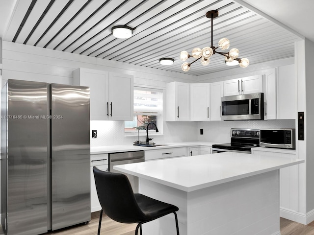 kitchen with a center island, sink, decorative light fixtures, white cabinets, and appliances with stainless steel finishes