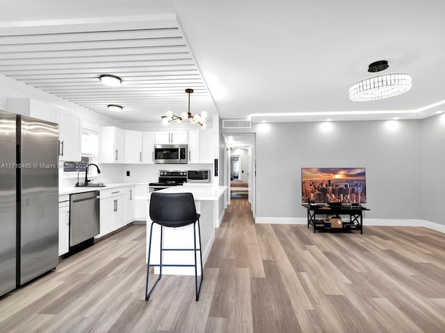 kitchen with white cabinetry, hanging light fixtures, an inviting chandelier, light hardwood / wood-style flooring, and appliances with stainless steel finishes