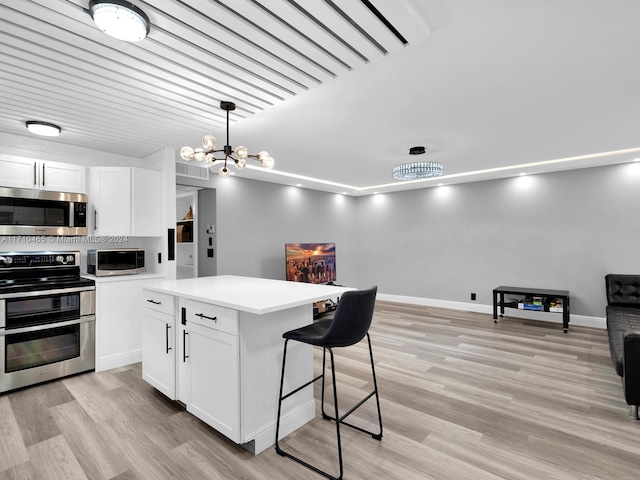 kitchen featuring a center island, hanging light fixtures, light hardwood / wood-style floors, white cabinetry, and stainless steel appliances