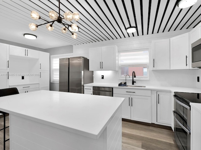 kitchen with white cabinets, stainless steel appliances, an inviting chandelier, and sink