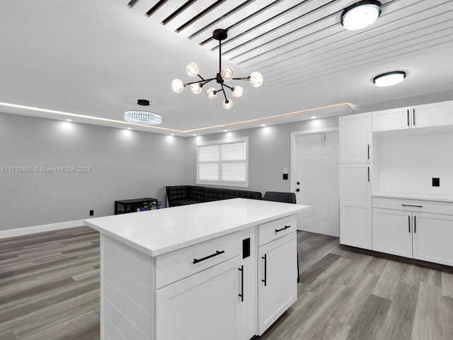 kitchen featuring pendant lighting, white cabinets, light wood-type flooring, a notable chandelier, and a kitchen island