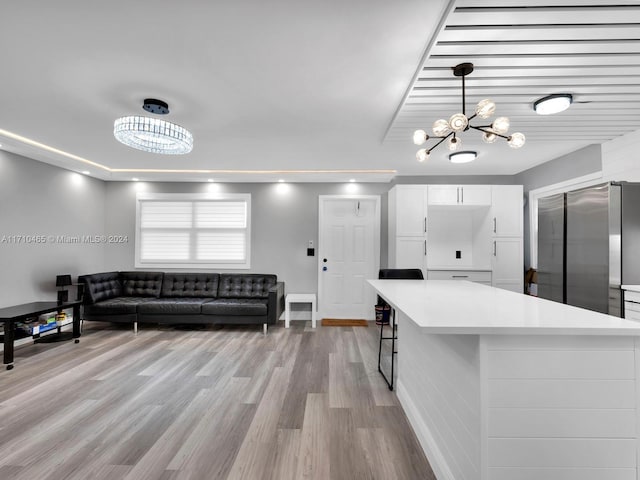 kitchen featuring stainless steel refrigerator, an inviting chandelier, pendant lighting, light hardwood / wood-style floors, and white cabinets