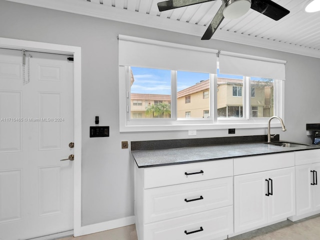 kitchen with white cabinets, sink, ceiling fan, ornamental molding, and beam ceiling