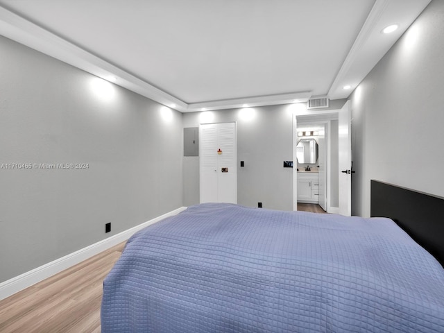 bedroom with hardwood / wood-style flooring, a closet, sink, and ensuite bath