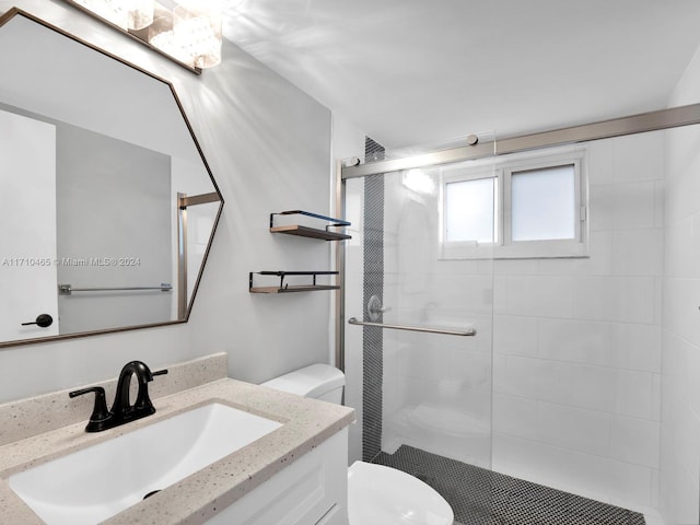 bathroom featuring vanity, toilet, and a shower with door