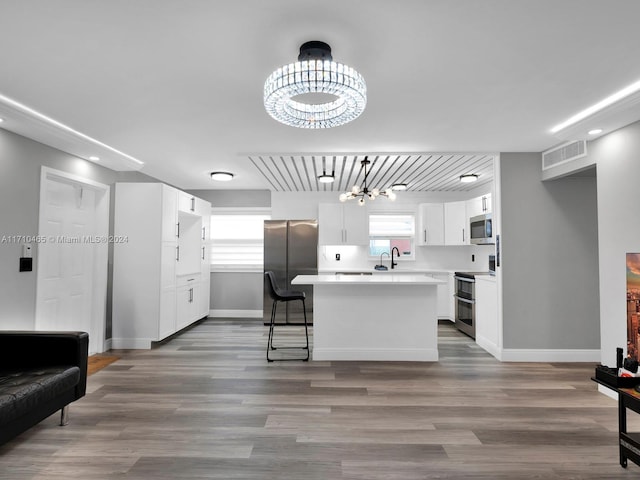 kitchen featuring a center island, white cabinets, light hardwood / wood-style flooring, appliances with stainless steel finishes, and a chandelier