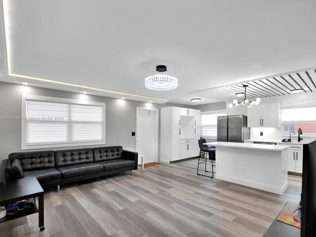 living room with sink, light hardwood / wood-style flooring, and a notable chandelier