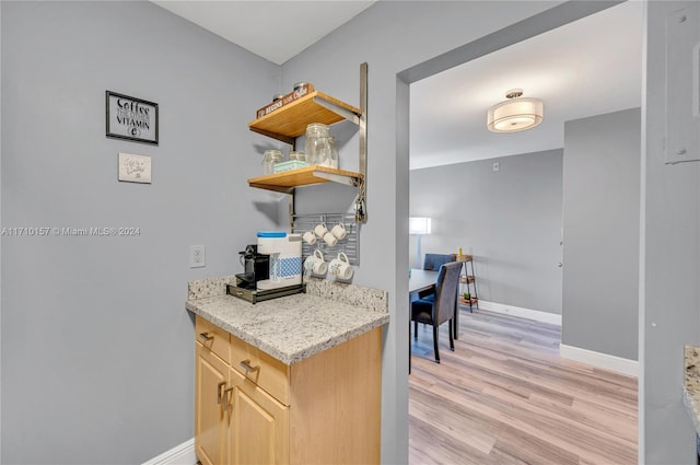 kitchen with light brown cabinets, light stone countertops, and light hardwood / wood-style flooring