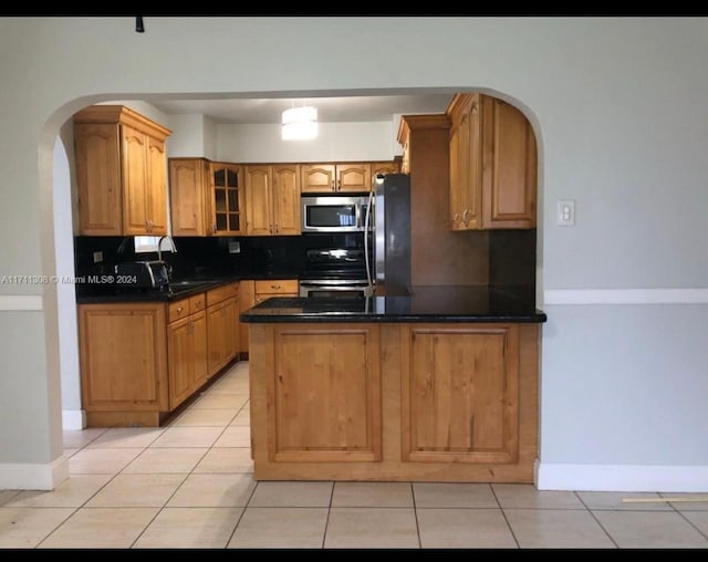 kitchen with tasteful backsplash, kitchen peninsula, light tile patterned floors, and stainless steel appliances