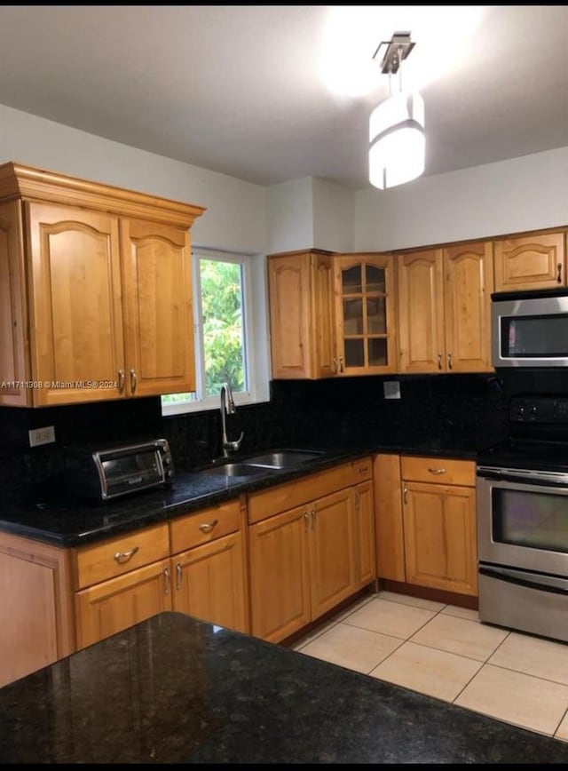 kitchen with light tile patterned flooring, appliances with stainless steel finishes, backsplash, and sink