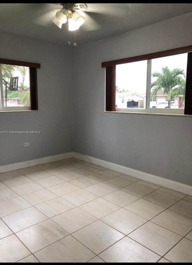 unfurnished room with a wealth of natural light, light tile patterned flooring, and ceiling fan