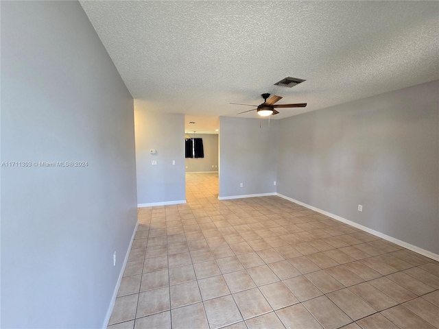 spare room with ceiling fan, light tile patterned flooring, and a textured ceiling