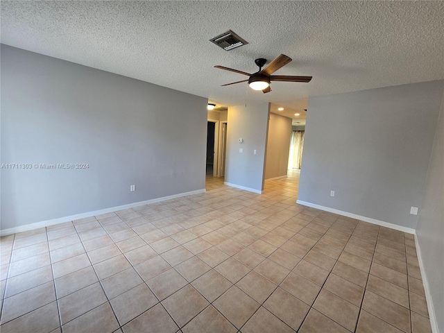 spare room with a textured ceiling, ceiling fan, and light tile patterned flooring