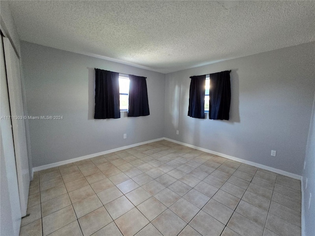 tiled empty room featuring a textured ceiling