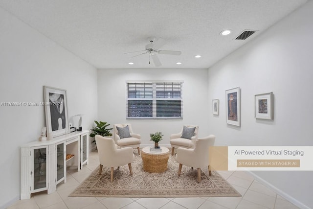 living area featuring ceiling fan, light tile patterned floors, and a textured ceiling