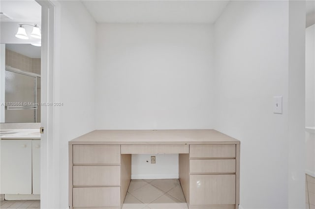 unfurnished office with built in desk and light tile patterned floors